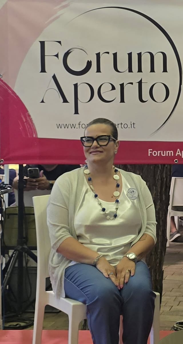 Melania Toraldo, presidente dell'APS Famiglie in BLU, davanti al banner di Forum Aperto